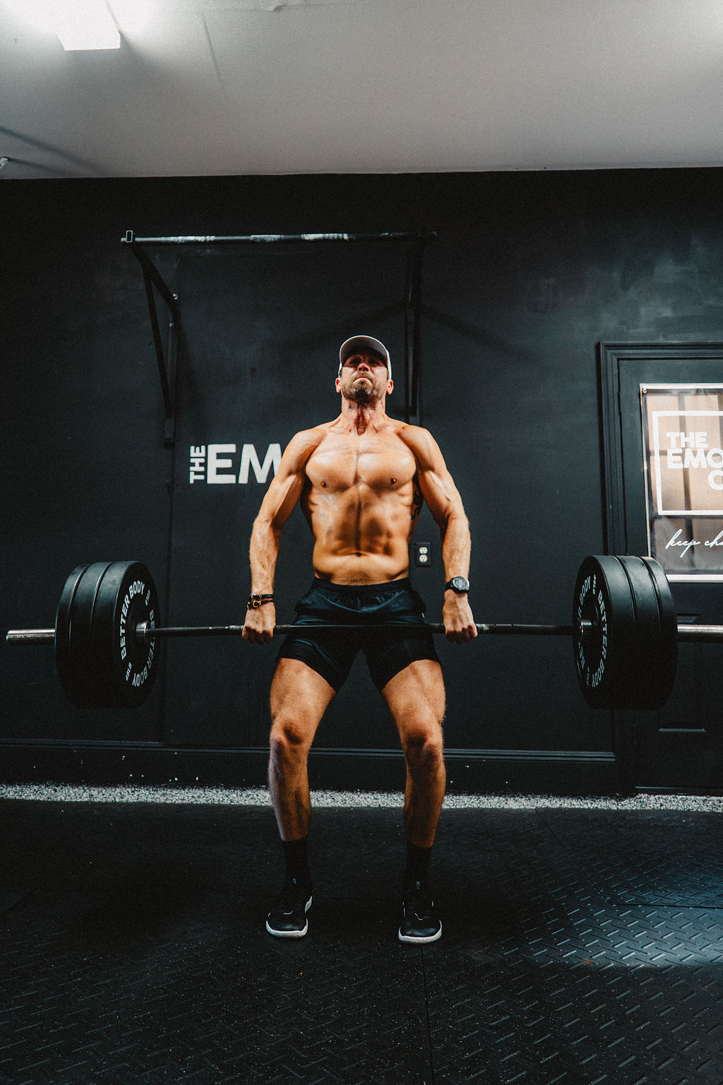 Athlete pulling a heavy deadlift under the lights in The EMOM Co. gym